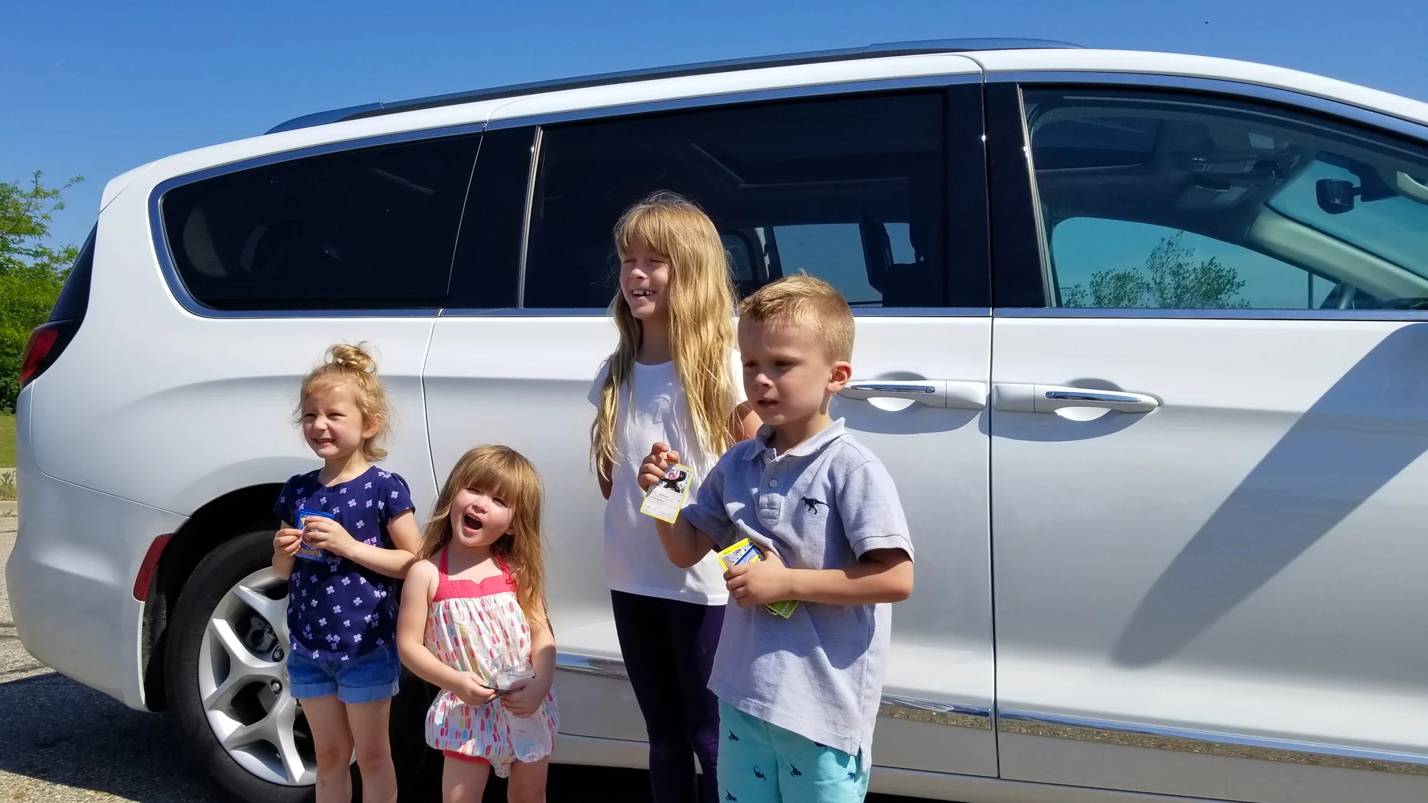Traveling with kids in a car. Young kids in front of a white van on a roadtrip.