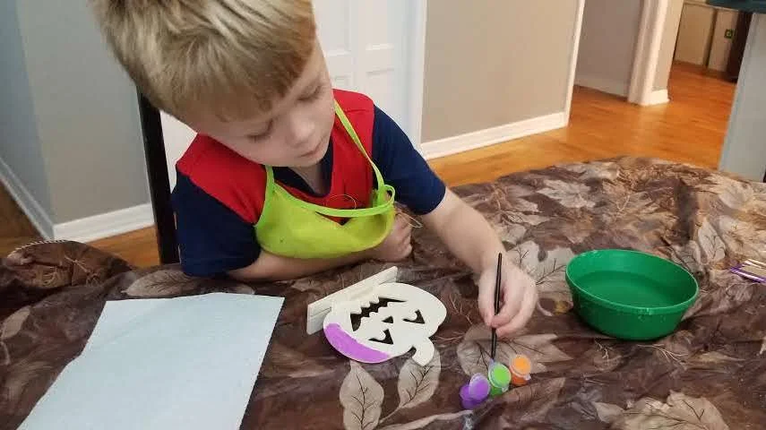 Toddler boy painting while using painting with toddlers tips and tricks