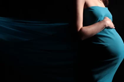 Maternity photography of belly in teal fabric with third trimester symptoms