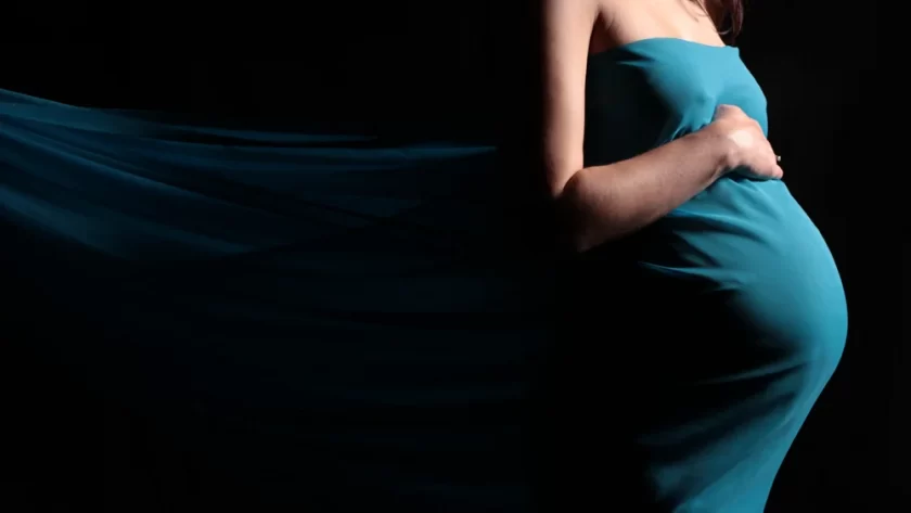 Maternity photography of belly in teal fabric with third trimester symptoms