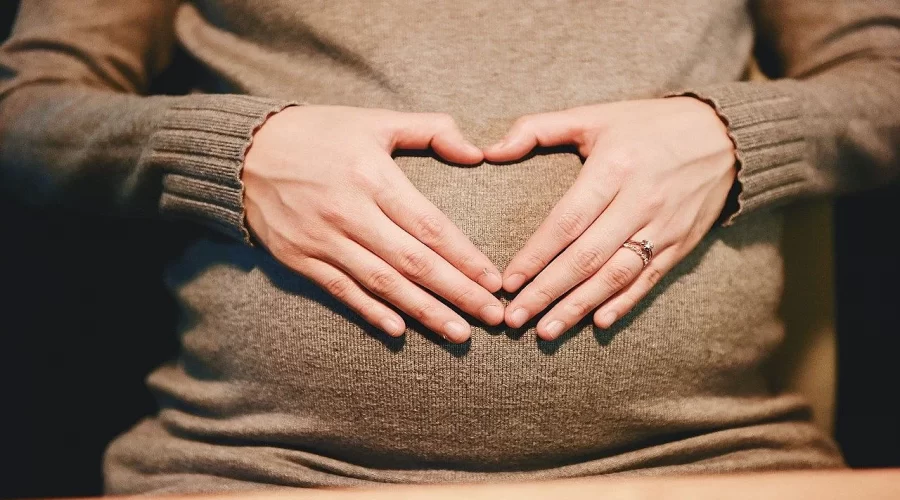 Woman holding hands in heart shape on belly for helpful pregnancy gifts for first time moms